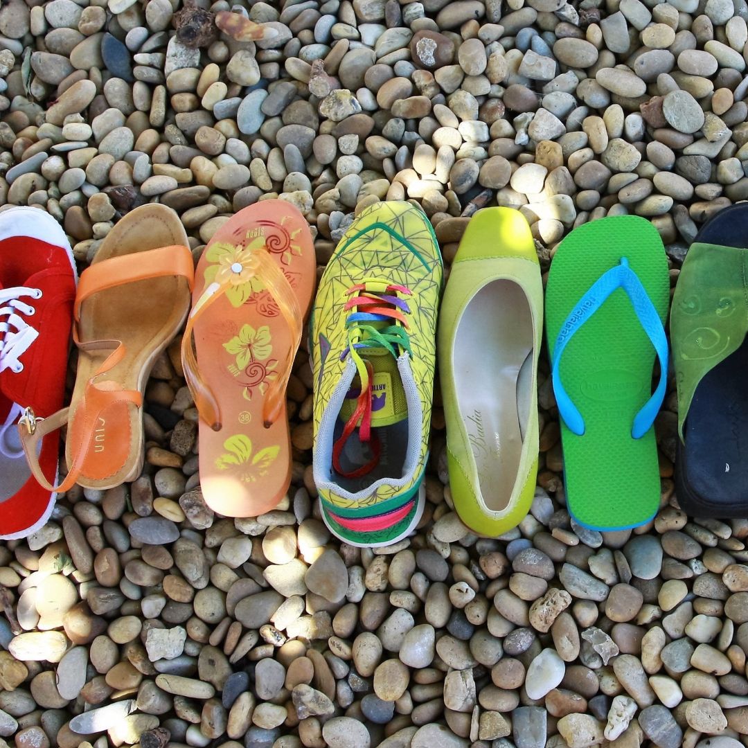 a row of colourful shoes lined up on pebbles