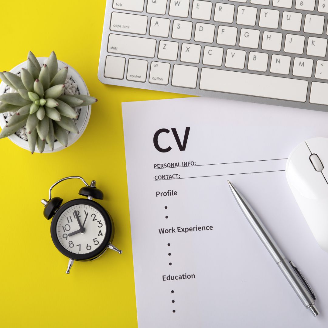 a yellow table with a CV, clock, plant, keyboard and mouse on it