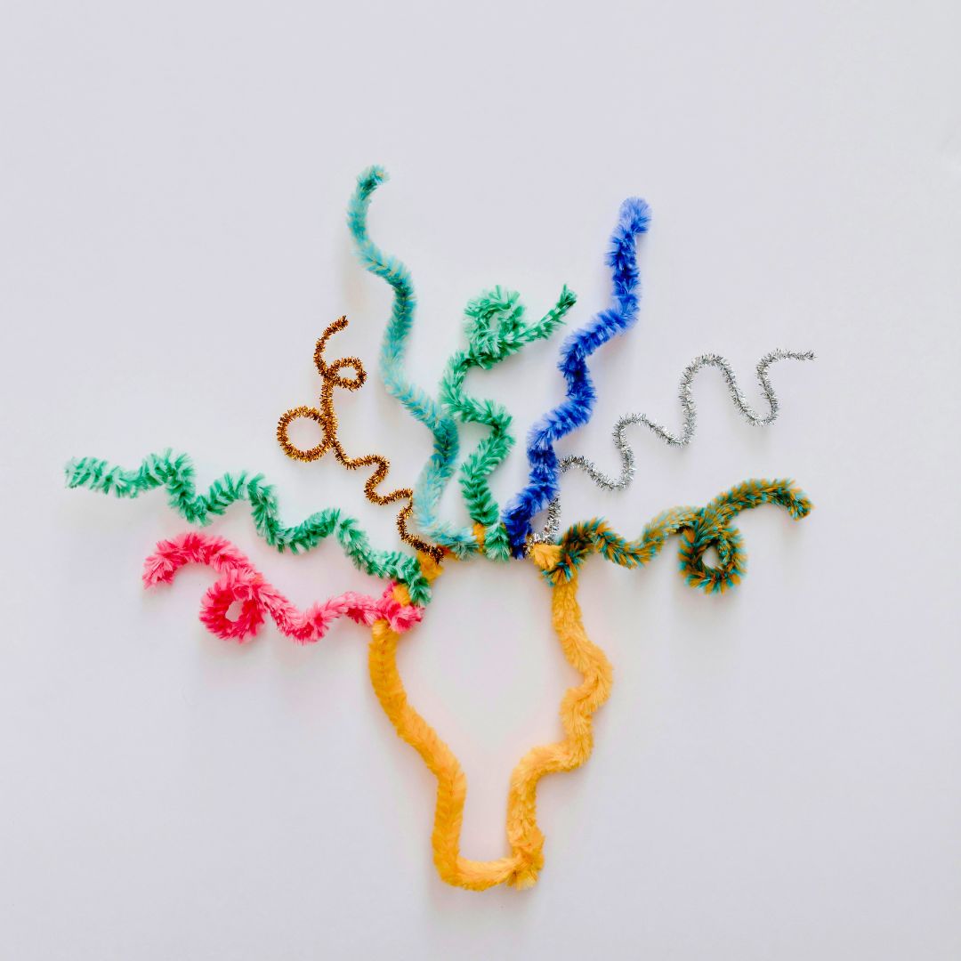 colourful yarn art depicting a head with squiggles coming out of the brain on a white surface